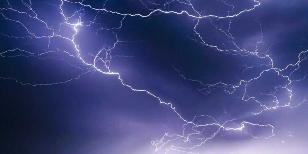 A purple sky with some lightning in the background