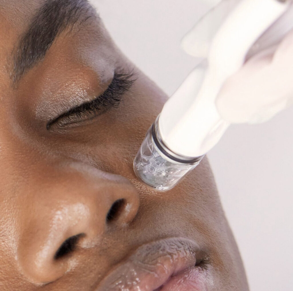 A woman is getting her face cleaned with an electric device.