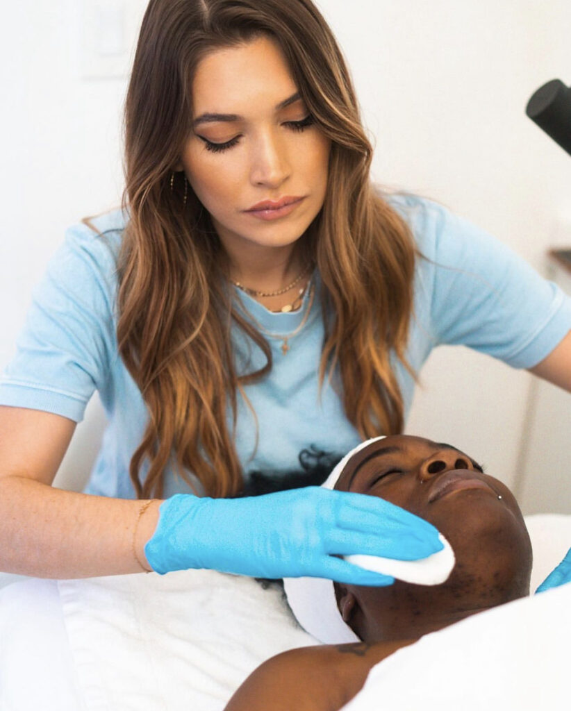 A woman in blue shirt and gloves on top of a man.