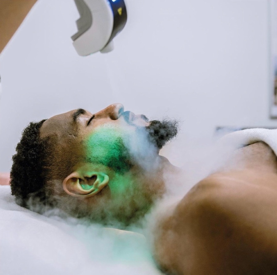 A man with green hair is lying in the shower.