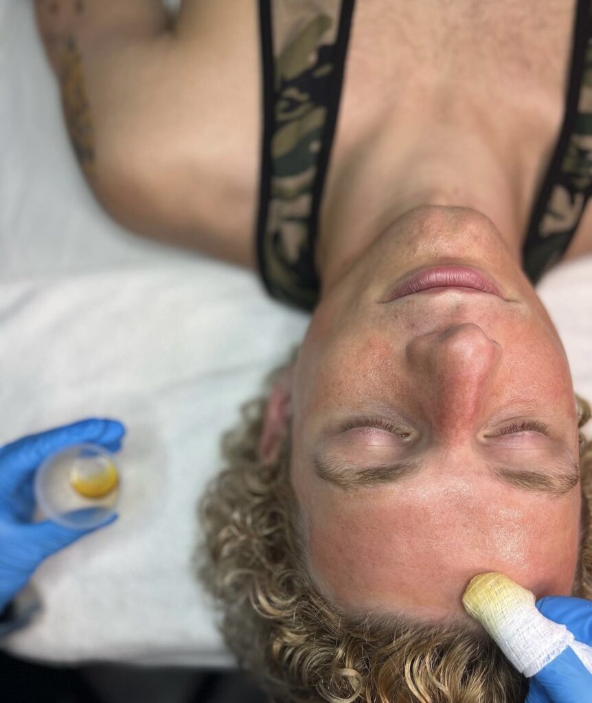 A man laying down with an ear piercing.