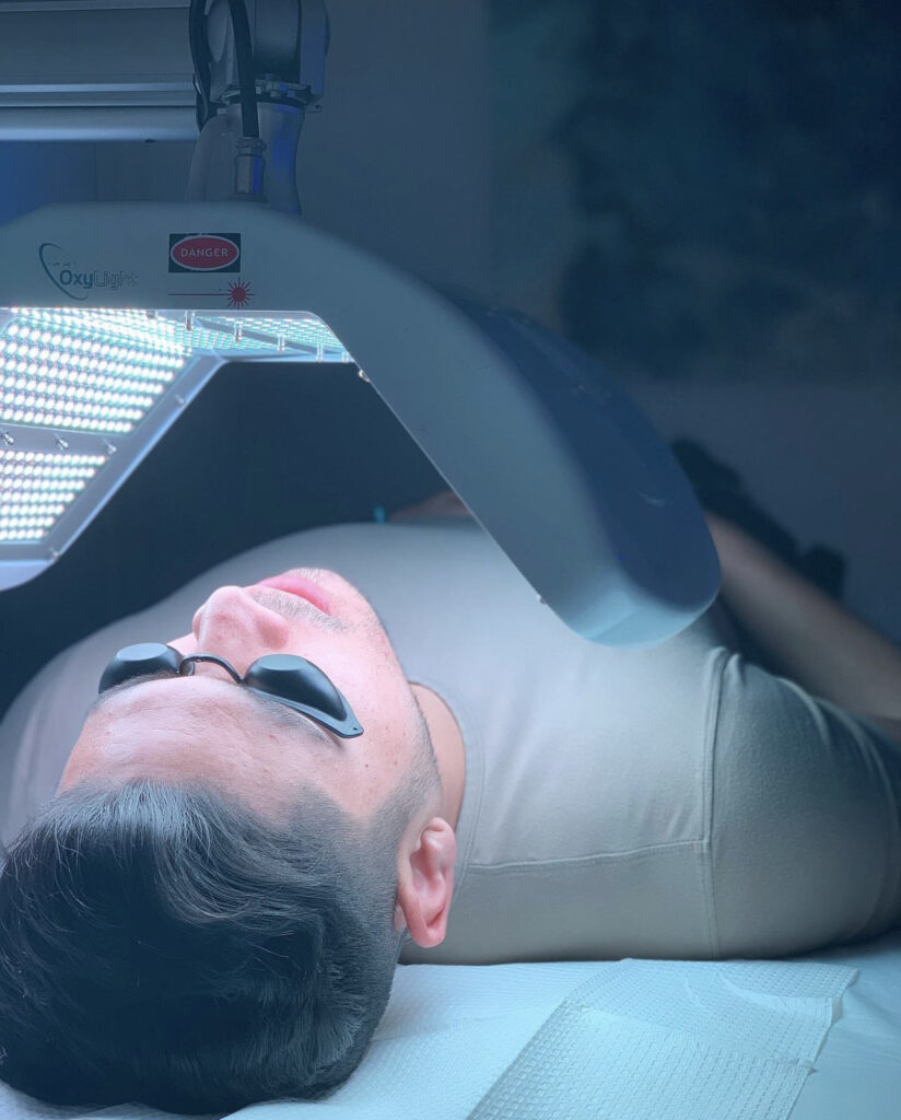 A man laying down with an open laptop on his head.